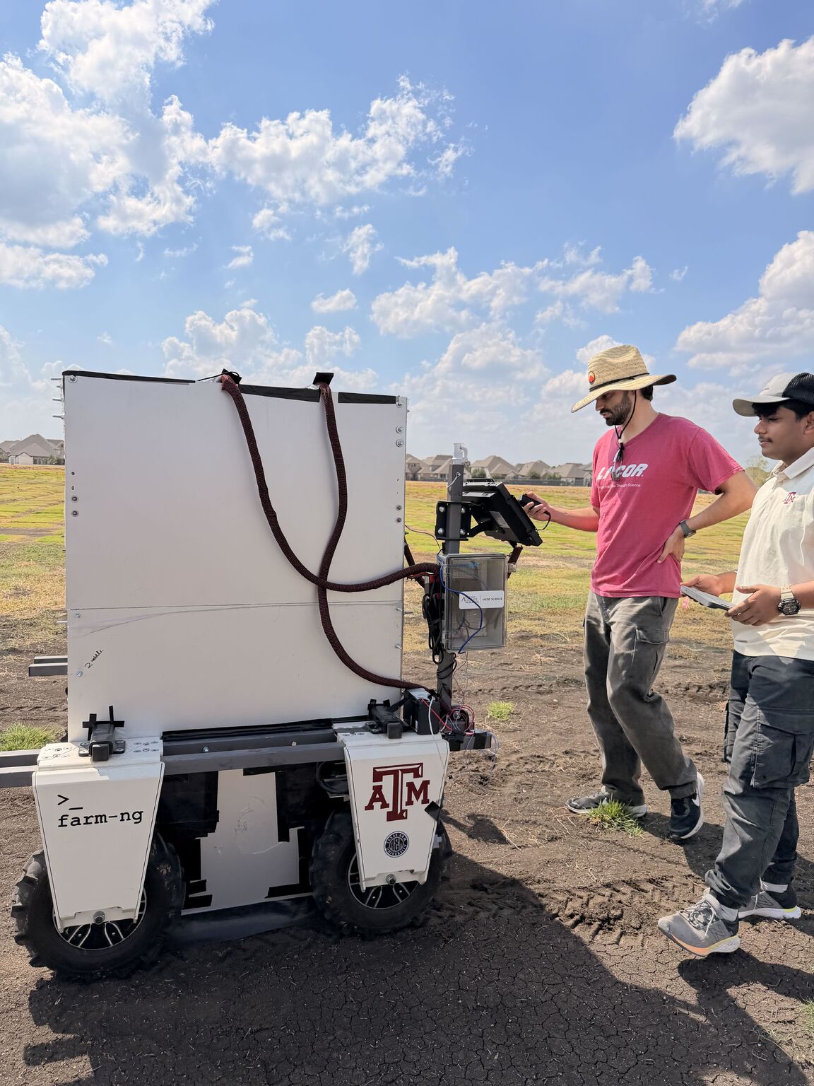 Team members operating Turfbot V2.0 with its light-box assembly in a turfgrass field.